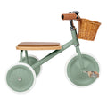 Green children's tricycle with a wooden seat and basket on a white background